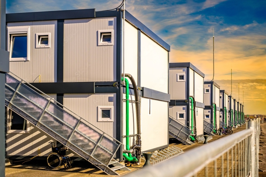 Row of modular buildings with stairs and pipes.